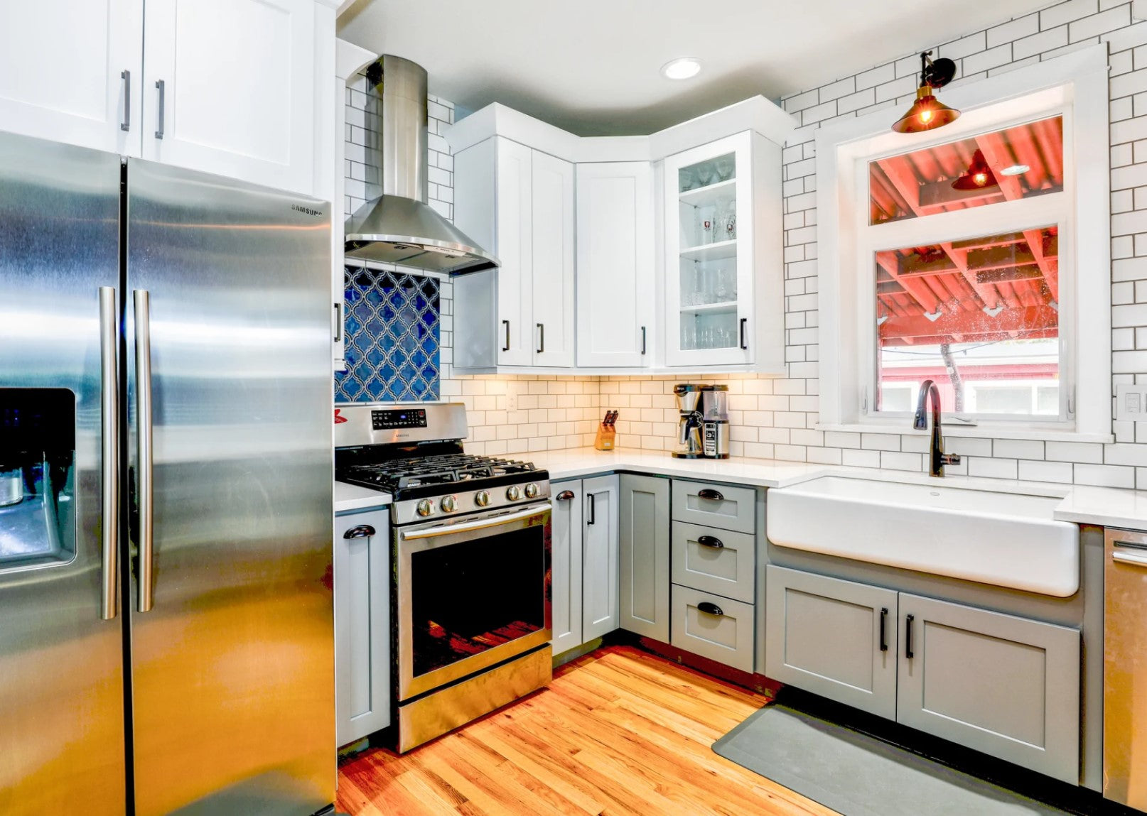 Bright kitchen with brushed metal fridge and stove white sink and cabinets window to outside