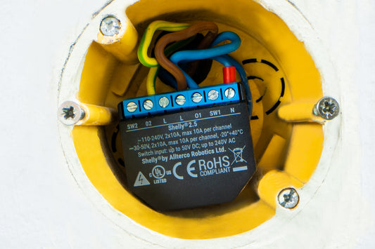 Shelly 2.5 relay with wiring inside yellow flushbox on white wall