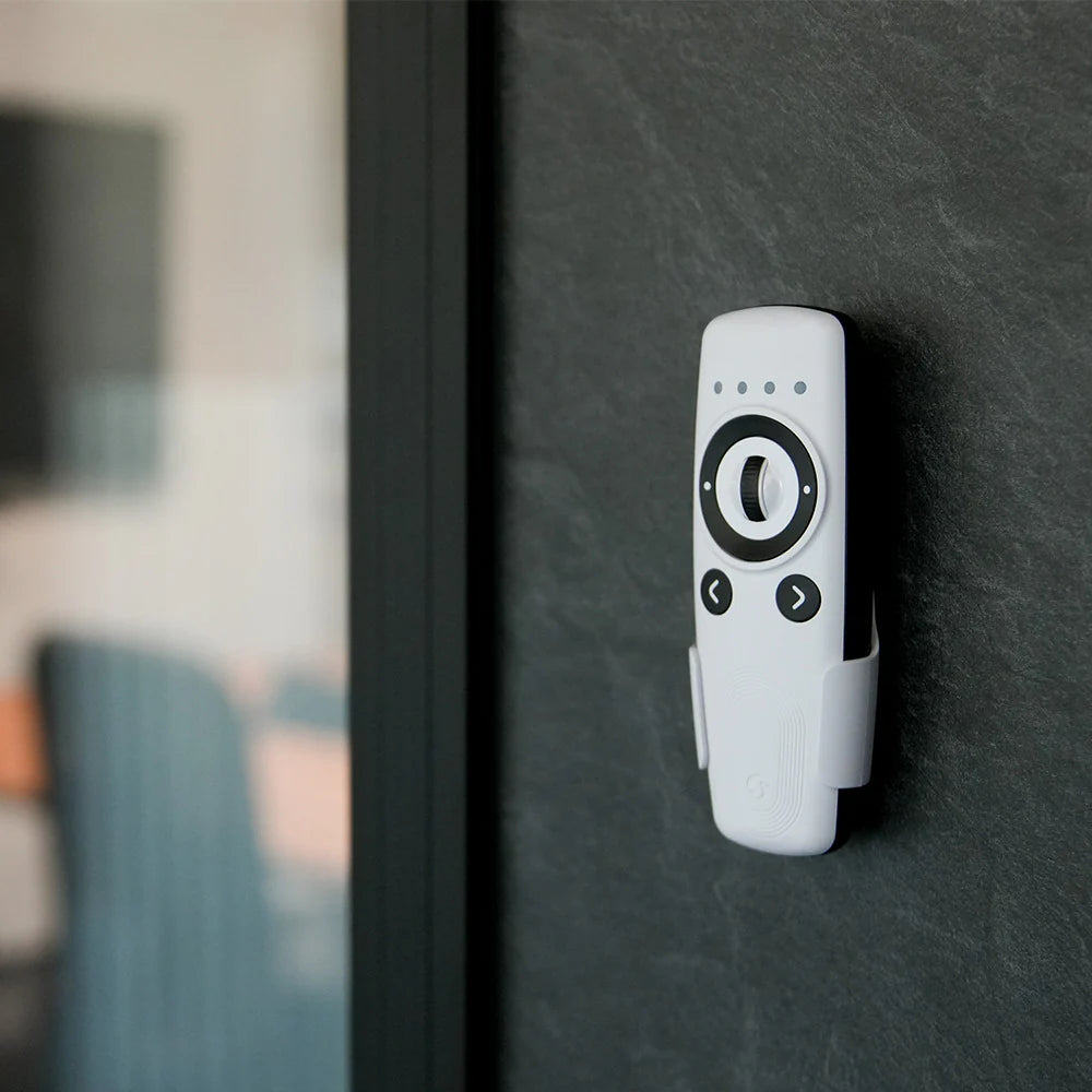 White remote control with black buttons on a dark surface | Lykalyte