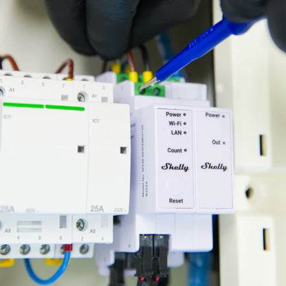 Person using a blue tool to test or adjust electronic components on a panel with 'Shelly' devices. Shelly Pro 3EM 3CT 63 | Lykalyte